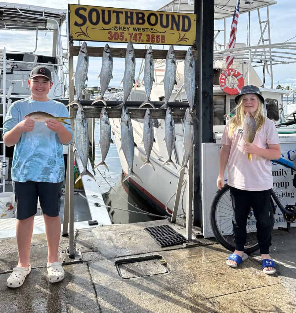 2 children on the dock with a rack full of fish