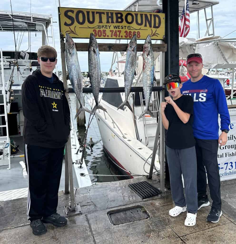 3 boys with Kingfish on the rack on the dock